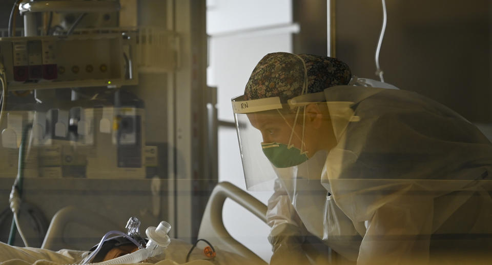 A medical workers comforts a coronavirus patient while wearing PPE.