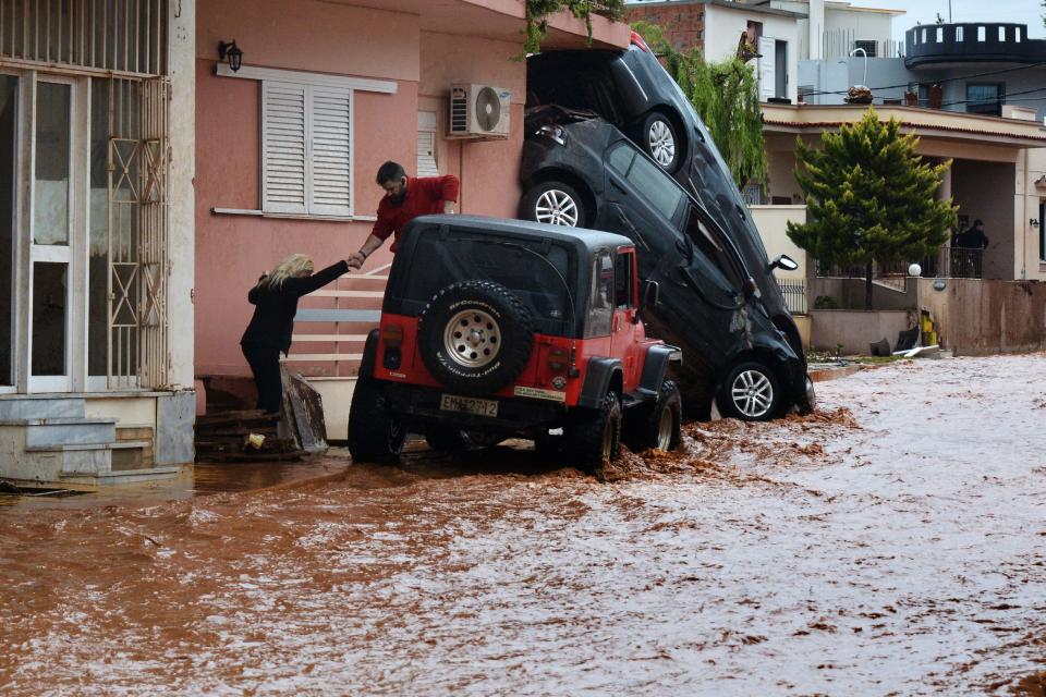 <p>A man helps evacuate a woman from a flooded street in Mandra, northwest of Athens, on Nov. 16, 2017. (Photo: Dimitris Lambropoulos/AFP/Getty Images) </p>