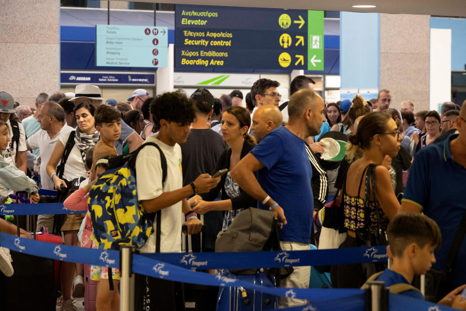 Tourists line up in check-in counters as they wait for departing planes at the airport, after being evacuated following a wildfire on the island of Rhodes, Greece, July 24, 2023. REUTERS/Nicolas Economou