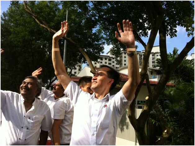 PAP's Dr Koh Poh Koon and company wave as the sun shines down. But few supporters can be seen on the road.