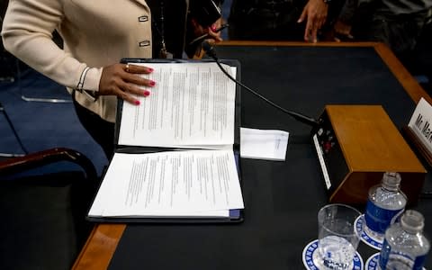 An aide to Facebook CEO Mark Zuckerberg closes a binder of notes left on the table  - Credit: AP