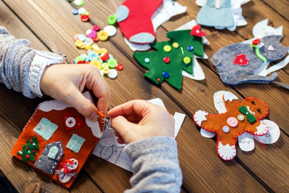 Person wearing a grey sweater making felt Christmas ornaments.