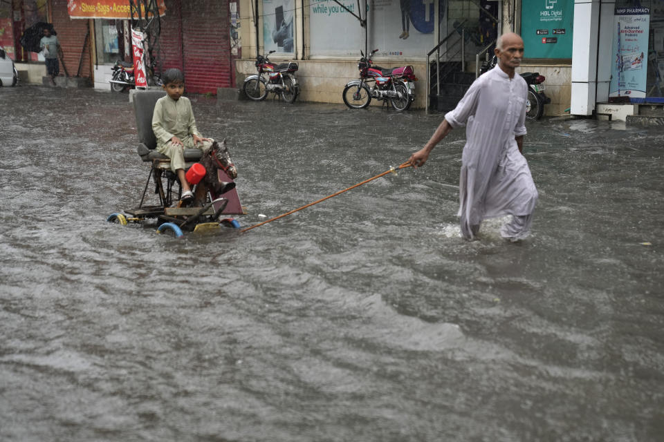 A man pulls a boy on a cart down a flooded road, amid heavy monsoon rainfall in Lahore, Pakistan, July 5, 2023. / Credit: K.M. Chaudary/AP