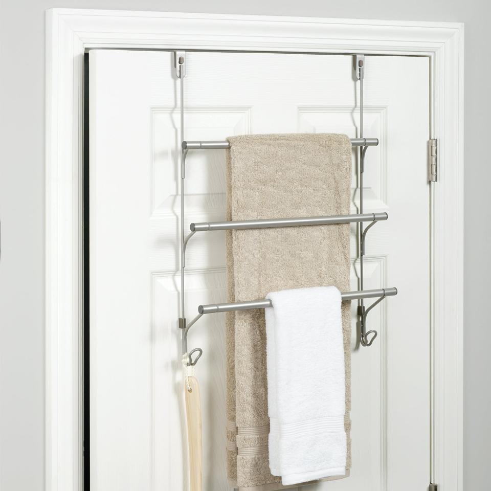 the towel bar with three rungs on the back of a bathroom door holding multiple towels