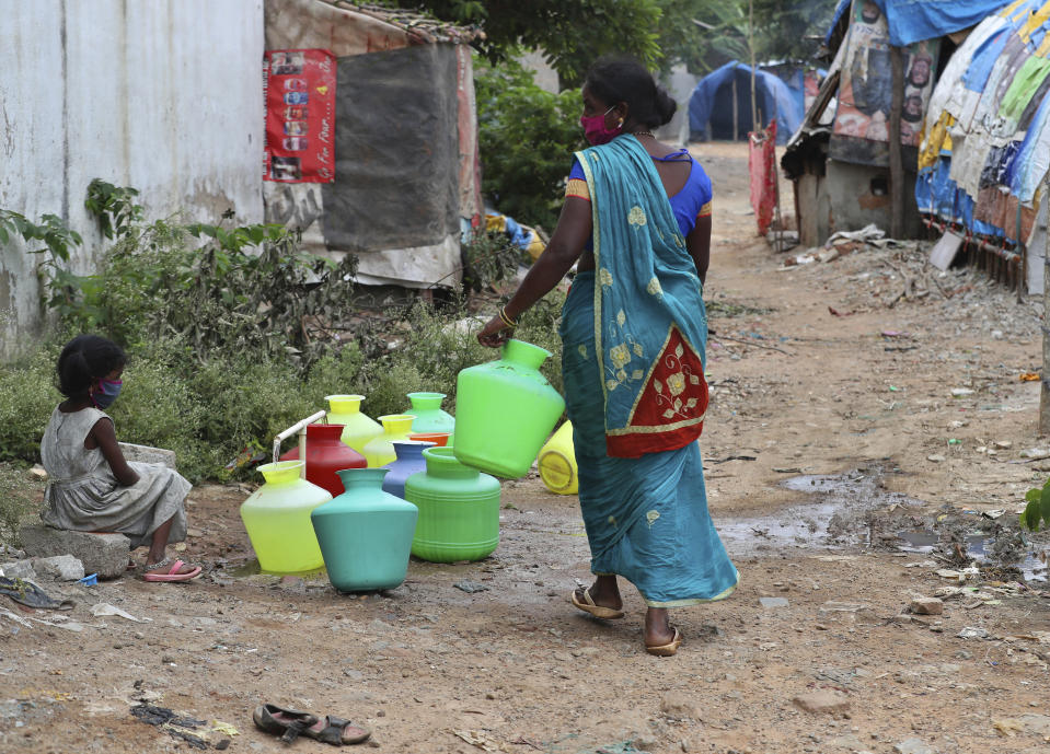 Five-year-old Shanthi, left, granddaughter of Padmavathi who died of COVID-19, collects potable water at a public tap near her family hut at a slum in Bengaluru, India, Thursday, May 20, 2021. Padmavathi collected hair, taking it from women's combs and hairbrushes to later be used for wigs. She earned about $50 a month. (AP Photo/Aijaz Rahi)