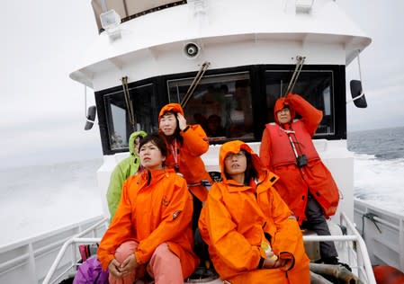 Tourists on a whale watching tour boat look for whales in the sea near Rausu