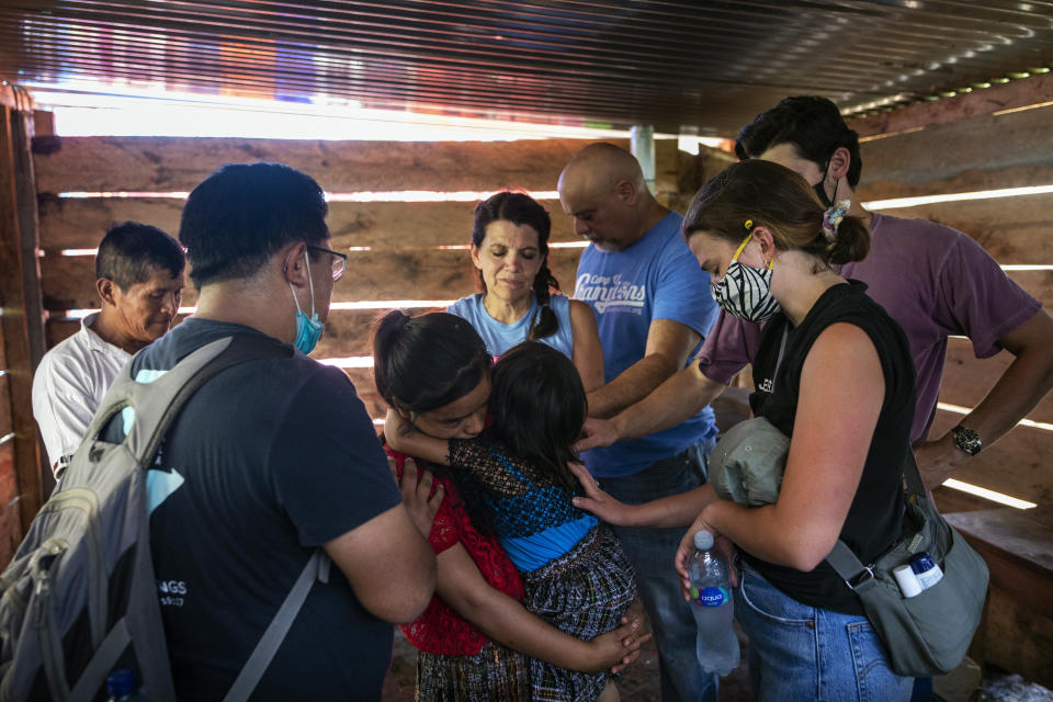CrossPoint Baptist church members, the Leonardi family from Argo, Alabama, pray over Ofelia Cal Jom, and her younger sister Dora, after installing a cinder block stove in their home, in the makeshift settlement Nuevo Queja, Guatemala, Monday, July 12, 2021. (AP Photo/Rodrigo Abd)