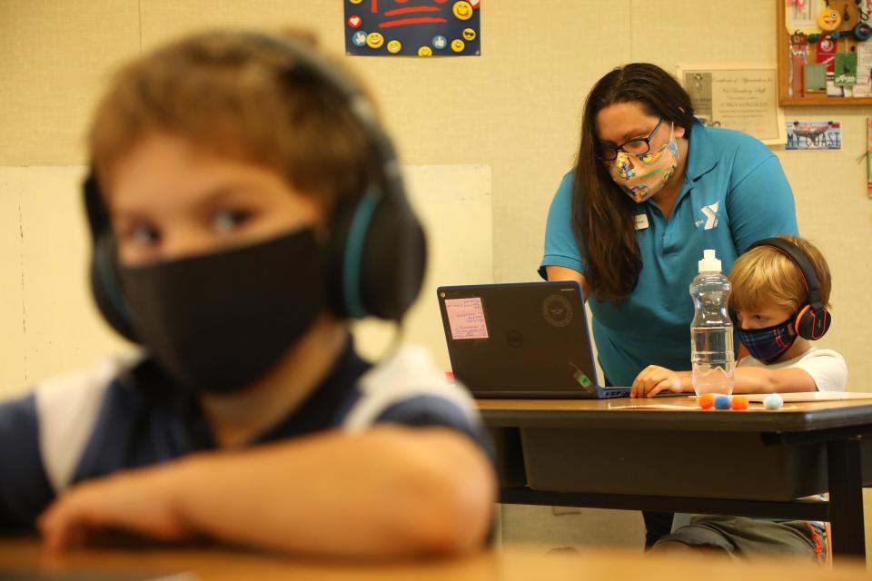 TORRANCE, CA - SEPTEMBER 17, 2020 - - Cassie Buzze, a site director with the YMCA and teacher, helps Tristan Wild with an exercise at the Anza Elementary School campus in Torrance on September 17, 2020. Anza Elementary School is one of many schools that are reformatting and rebranding as camps, enrichment programs and daycare, bringing students back to closed campuses for a fee. Torrance Unified School District is one of many that now offers fee-based, in person enrichment for its elementary school students, through the YMCA. (Genaro Molina / Los Angeles Times via Getty Images)