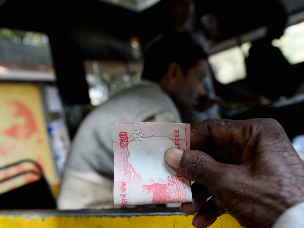 An Indian customer holds a twenty rupee note at a food stall in New Delhi: AFP/Getty Images