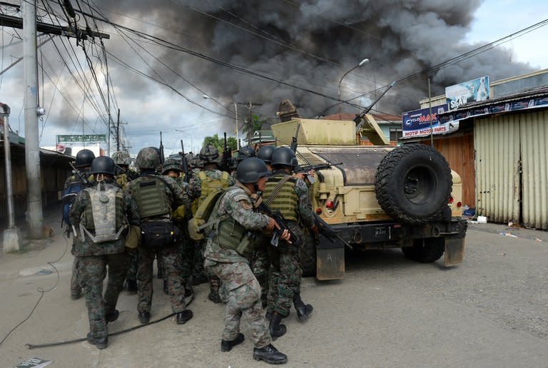 Philippines forces take cover during a fire fight with Muslim rebels in Zamboanga on September 12, 2013. At least 22 people have been killed and 52 wounded in five days of fighting, while 19 of the gunmen have surrendered or been captured