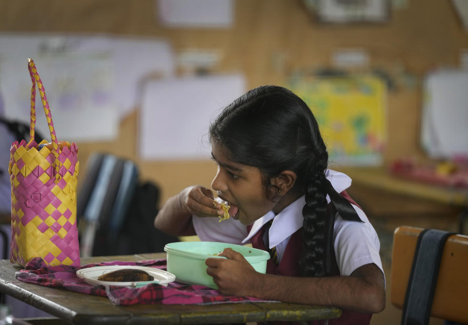 A primary student eats a free meal given at the school in Dalukana village in Dimbulagala, about 200 kilometres north east of Colombo, Sri Lanka, Monday, Dec. 12, 2022. Due to Sri Lanka's current economic crisis families across the nation have been forced to cut back on food and other vital items because of shortages of money and high inflation. Many families say that they can barely manage one or two meals a day. (AP Photo/Eranga Jayawardena)