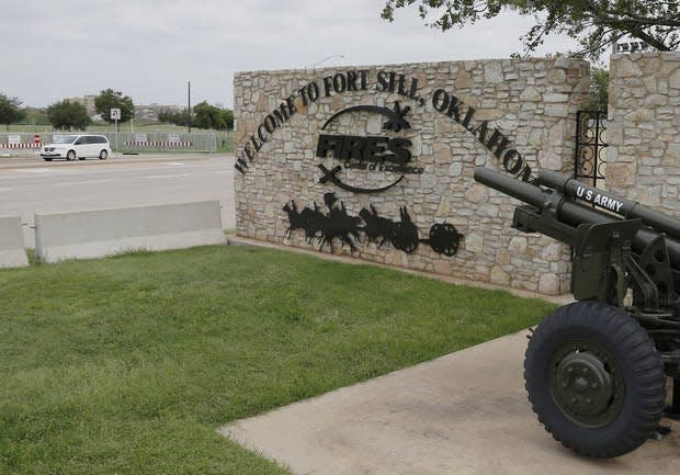 In this June 17, 2014, photo, a vehicle drives by a sign at Scott Gate, one of the entrances to Fort Sill.