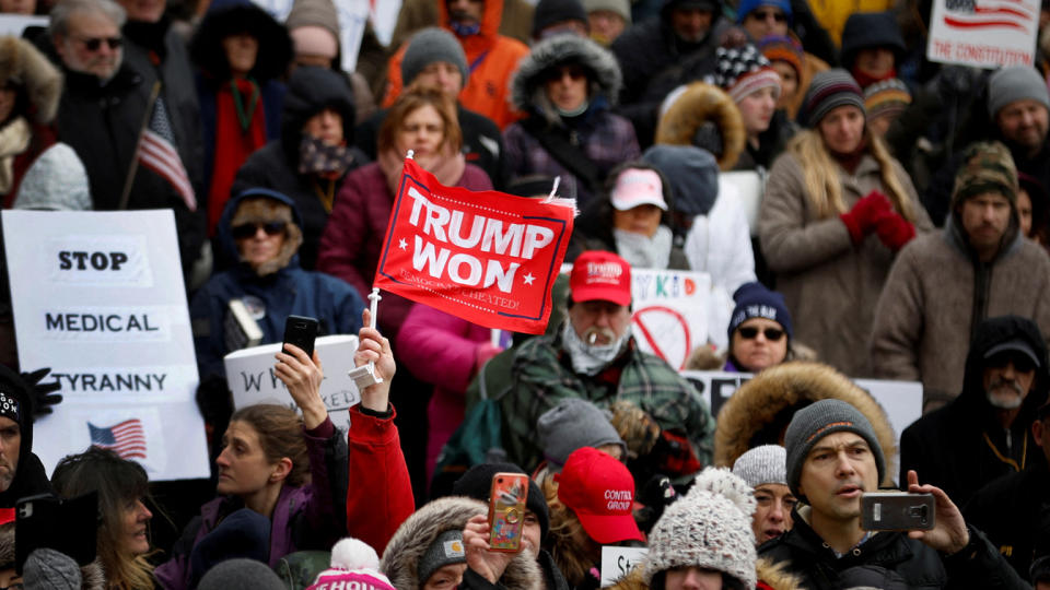 A protester in red holds a red flag reading 