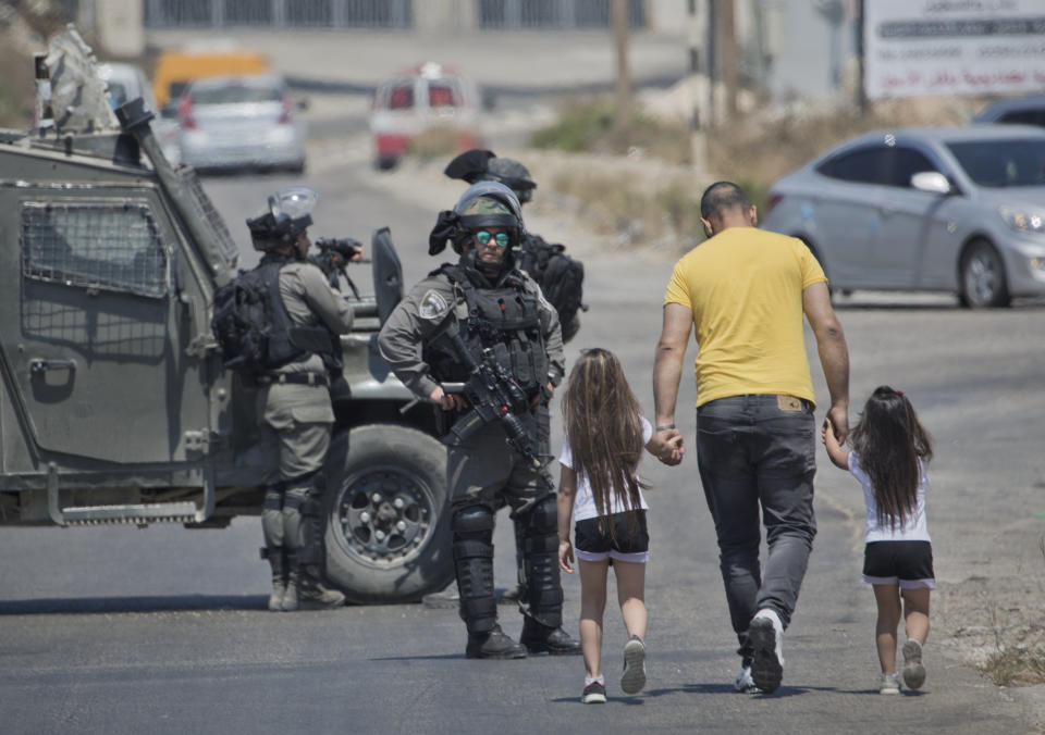 Israeli forces close the roads near the area of an attack, west of the West Bank city of Ramallah, Friday, Aug. 23. 2019. An explosion Friday near a West Bank settlement that Israel said was a Palestinian attack killed a 17-year-old Israeli girl and wounded her brother and father, Israeli authorities said. (AP Photo/Nasser Nasser)