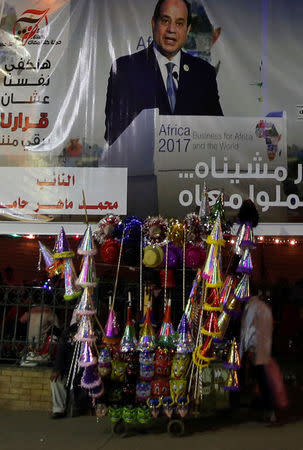 A vendor called "Tratyer", selling decorative hats, sits in front of a poster of Egypt's President Abdel Fattah al-Sisi for the upcoming presidential election in old Islamic Cairo, Egypt, March 8, 2018. REUTERS/Amr Abdallah Dalsh