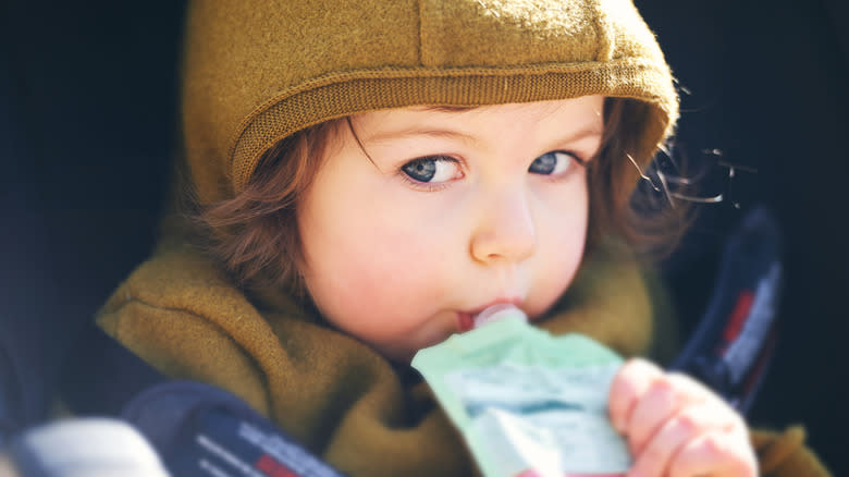 Young child drinking fruit purée pouch