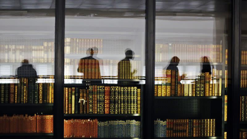 In this photo taken Wednesday, April 3, 2013, people are reflected in the windows of the British Library where old books are kept in London, Wednesday, April 3, 2013.