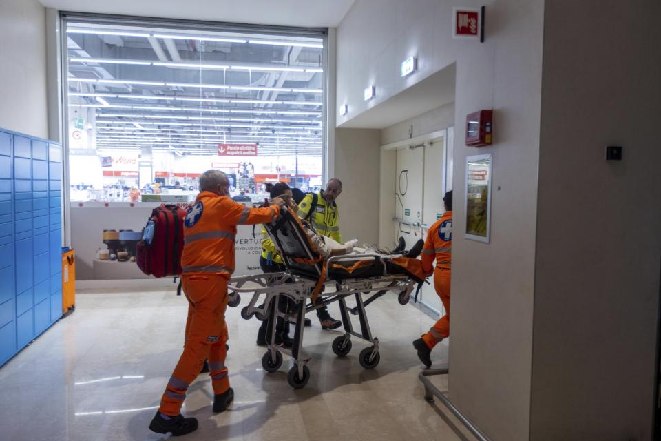 Emergency personnel wheel an injured person at the scene of an attack in Milan, Italy, Thursday Oct. 27, 2022. A man armed with a knife stabbed five people inside a shopping center south of Milan on Thursday. (LaPresse via AP)