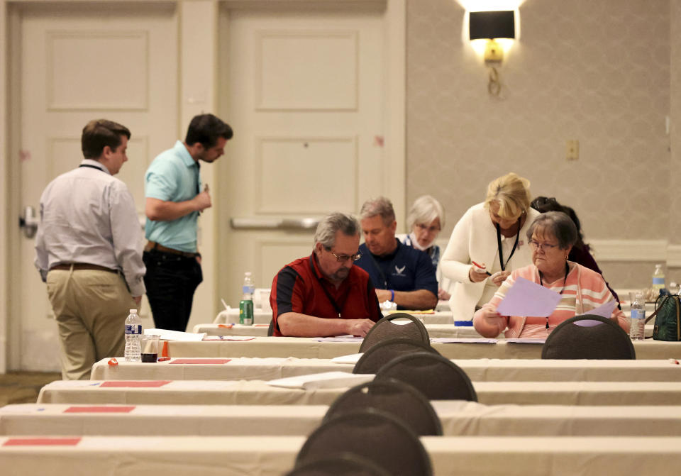 Tellers, sitting, work on counting ballots next to observers for the Virginia Republican Party primary at Richmond Marriott in Richmond, Va., on Sunday, May 9, 2021. (Daniel Sangjib Min/Richmond Times-Dispatch via AP)