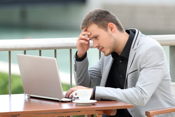 Young businessman reading something on his laptop, with a worried look on his face.