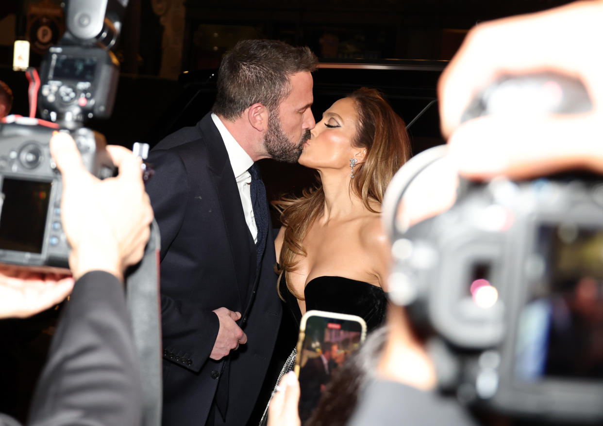 Ben Affleck and Jennifer Lopez kiss in front of cameras.