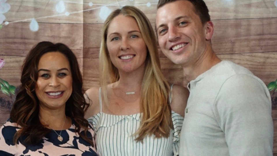 two women and a man smiling towards the camera