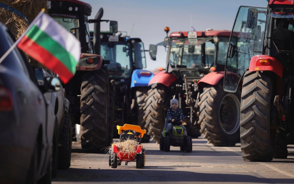 A child in a ride-on tractory plays among the real things during a protest in Girona, Spain