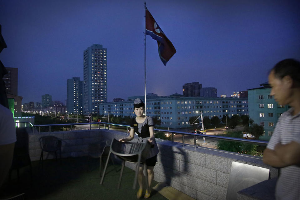 <p>A waitress moves a dining chair at a restaurant terrace that overlooks a residential street at dusk in Pyongyang, North Korea, June 19, 2017. (Photo: Wong Maye-E/AP) </p>