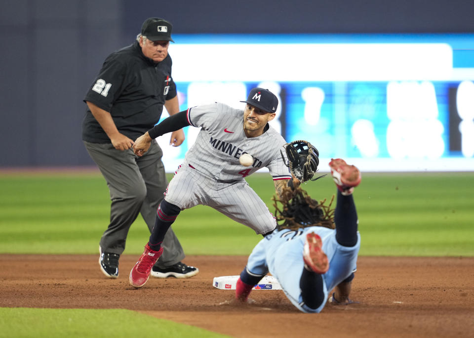 Toronto Blue Jays' Vladimir Guerrero Jr., right, gets caught stealing second base against Minnesota Twins shortstop Carlos Correa (4) during the seventh inning of a baseball game in Toronto, Ontario, Friday, June 9, 2023. (Mark Blinch/The Canadian Press via AP)