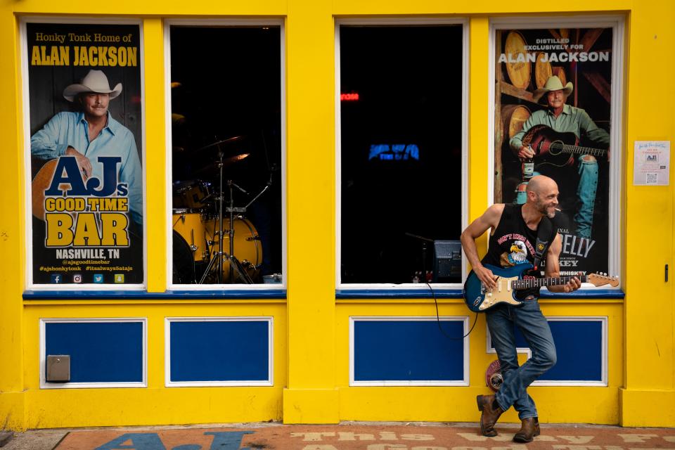 Guitarist Ryan Tolson pops of out the window to smoke while still performing at AJs Good Time Bar on Lower Broadway during the Let Freedom Sing! Music City July 4th event in Nashville, Tenn., Tuesday, July 4, 2023.