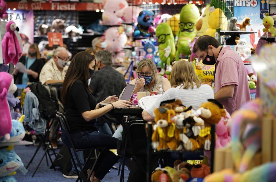 People meet a booth looking to buy items on the final day of the convention floor at the ASD Market Week convention Wednesday, Aug. 25, 2021, in Las Vegas. In pre-COVID times, business events like conferences and trade shows routinely attracted more than 1 billion participants and $1 trillion in direct spending each year. The pandemic brought those gatherings to a sudden halt, but now in-person meetings are on the rebound from Las Vegas to Beijing. (AP Photo/John Locher)