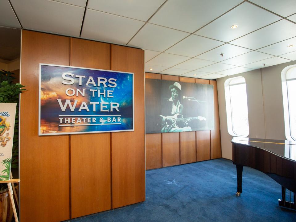 A piano in front of wall art and a sign that says "Stars on the water theater and bar."