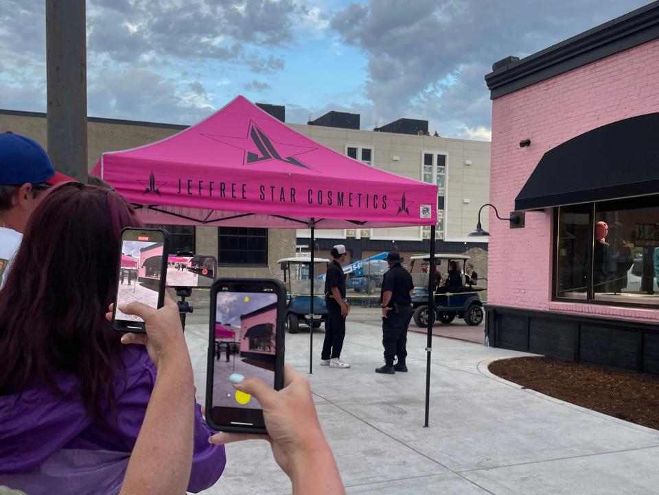 pink jeffree star cosmetics tent with many snapping photos from a line as Jeffree Star drives by in a golf cart