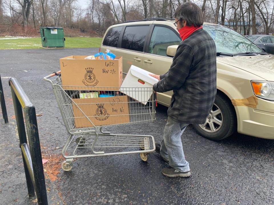 A volunteer pulls a cart of food and gifts during Alliance Salvation Army's drive thru distribution on Monday, Dec. 21, 2020.