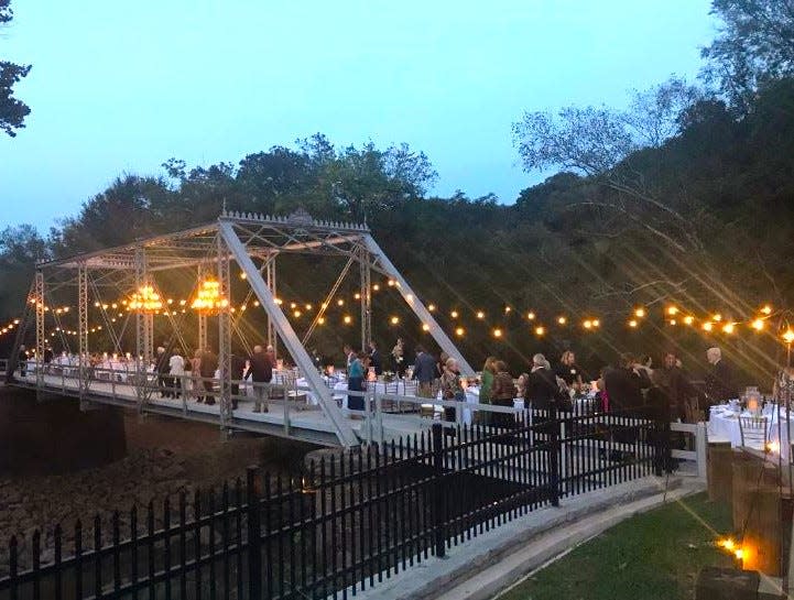 Night begins to fall as guests make their way to tables placed along a century-old bridge in Oconee Hill Cemetery.