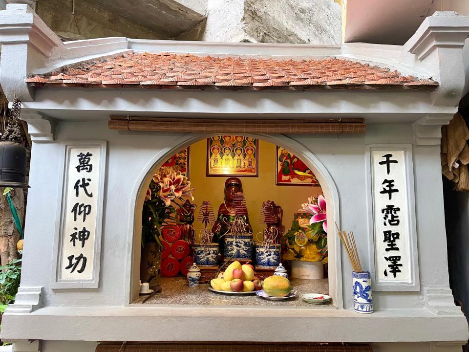 Shrine with incense and offerings at fish noodle restaurant in Hanoi Vietnam.