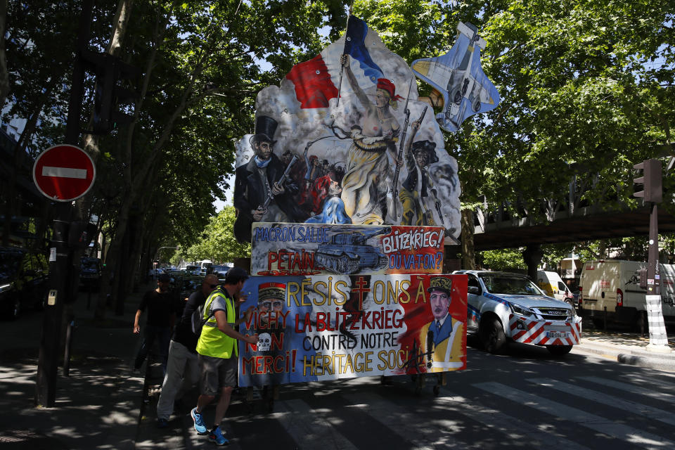 Yellow vest protestors push a giant banner referring to the "Liberty Leading the People" painting by Eugène Delacroix during a march, in Paris, Saturday, June 1, 2019. Yellow vest protests are taking place for the 29th consecutive week to challenge President Emmanuel Macron's economic policies. (AP Photo/Francois Mori)