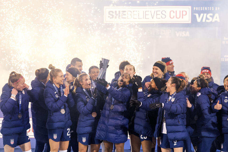 U.S. forward Catarina Macario, who won the SheBelieves Cup MVP award, hoists the SheBelieves Cup trophy while joined by teammates after their 5-0 win over Iceland in a soccer match Wednesday, Feb. 23, 2022, in Frisco, Texas. (AP Photo/Jeffrey McWhorter)