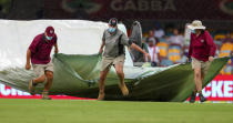 Ground staff bring covers onto the field as rain stops play on day four of the fourth cricket test between India and Australia at the Gabba, Brisbane, Australia, Monday, Jan. 18, 2021. (AP Photo/Tertius Pickard)