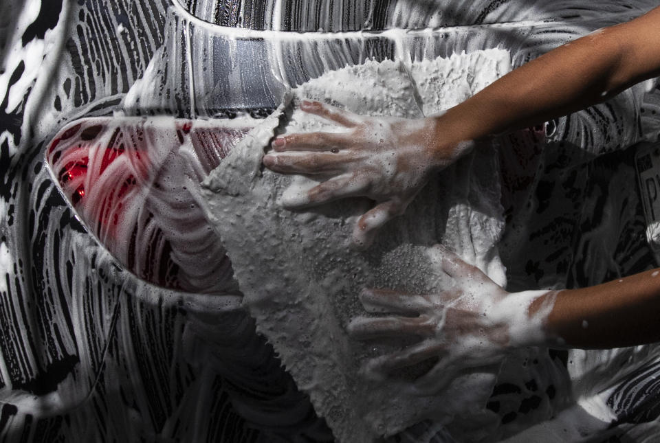 Fransisco Palomino washes a car as he works at the Lavakar car wash in Mexico City, Friday, July 31, 2020. Workers said the car was closed for three months during the COVID-19 related lockdown, and now after reopening only service about 10 cars a day, compared to 30 before the lockdown. (AP Photo/Marco Ugarte)