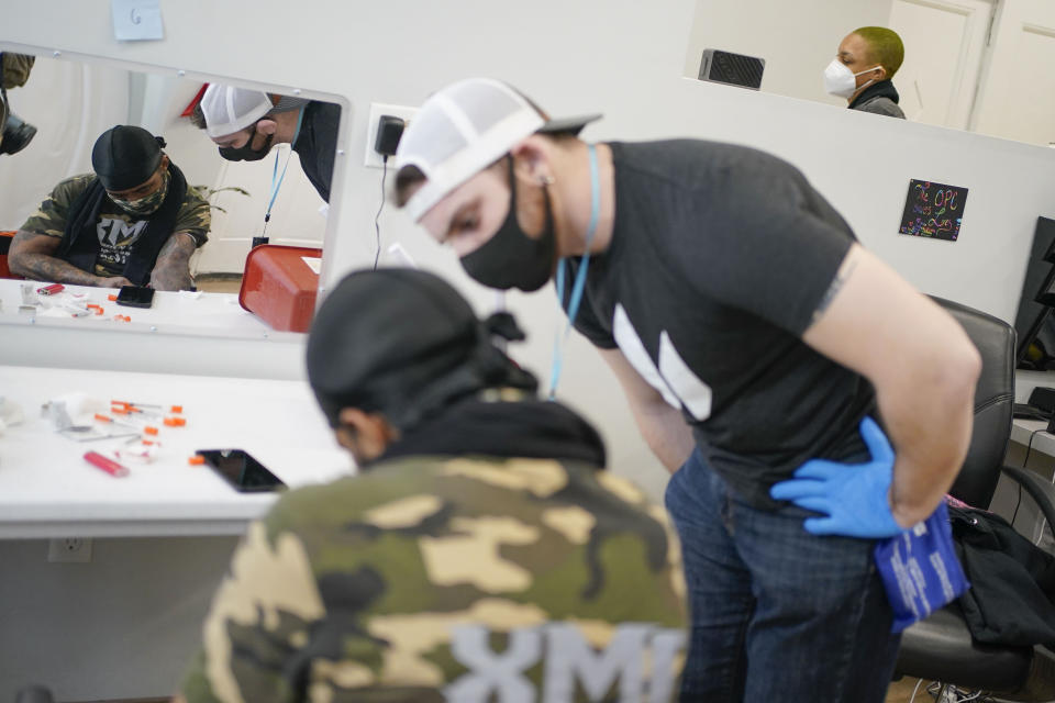 FILE - Brian Hackel, right, an overdose prevention specialist, helps Steven Baez, a client suffering addiction, find a vein to inject intravenous drugs at an overdose prevention center, OnPoint NYC, in New York, Feb. 18, 2022. Across the U.S., drug overdoses killed an estimated 100,000 people in 2021, according to federal health officials. That has pushed lawmakers in Colorado, New Mexico and Nevada to consider joining New York in allowing what are often called “overdose prevention centers" — spaces where people can use illicit drugs under the supervision of trained staff who could reverse an overdose if necessary. (AP Photo/Seth Wenig, File)