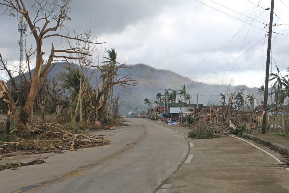 In this photo provided by the Philippine Coast Guard, toppled trees lie along an empty road in Surigao del Norte province, southern Philippines on Saturday, Dec. 18, 2021. The governor of an island province in the central Philippines said dozens of people died in the devastation wrought by Typhoon Rai in just half of the towns that managed to contact him, bringing the death toll in the strongest typhoon to batter the country this year to nearly 100. (Philippine Coast Guard via AP)