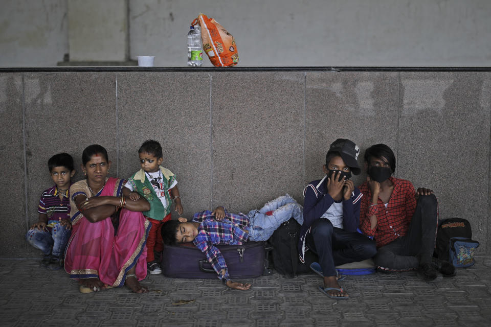 A boy sleeps on a suitcase as a migrant family from another state trying to return to their home wait sfor transportation to a railway station on the outskirts of New Delhi, India, Monday, May 18, 2020. India has recorded its biggest single-day surge in new cases of coronavirus. The surge in infections comes a day after the federal government extended a nationwide lockdown to May 31 but eased some restrictions to restore economic activity and gave states more control in deciding the nature of the lockdown. (AP Photo/Altaf Qadri)