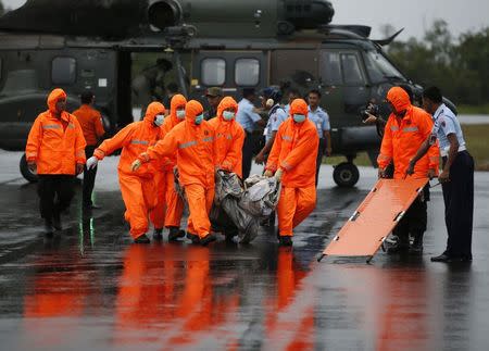 Search and Rescue crews carry part of AirAsia QZ8501 transported to shore by a Singapore Navy helicopter at the airbase in Pangkalan Bun, Central Kalimantan January 4, 2015. REUTERS/Darren Whiteside