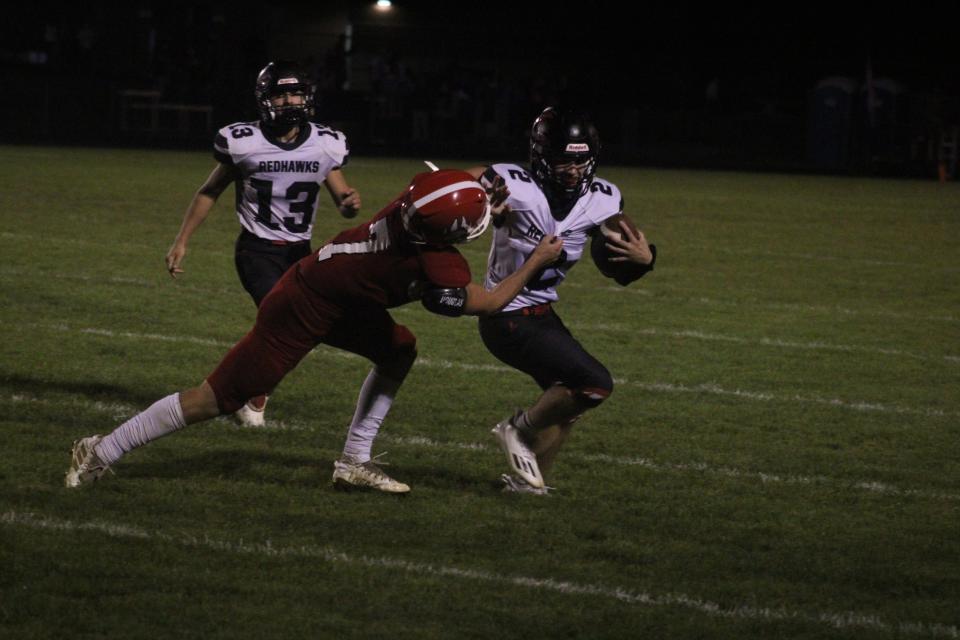 Saranac senior quarterback Sam Sterzick (No. 2) looks to evade a tackle from Laingsburg senior defensive back Lucas Matthews (No. 7) as Saranac junior running back Carson Hardy (No. 13) looks on during a varsity football game Friday, Sept. 22, at Laingsburg High School. Saranac won the game, 28-20.