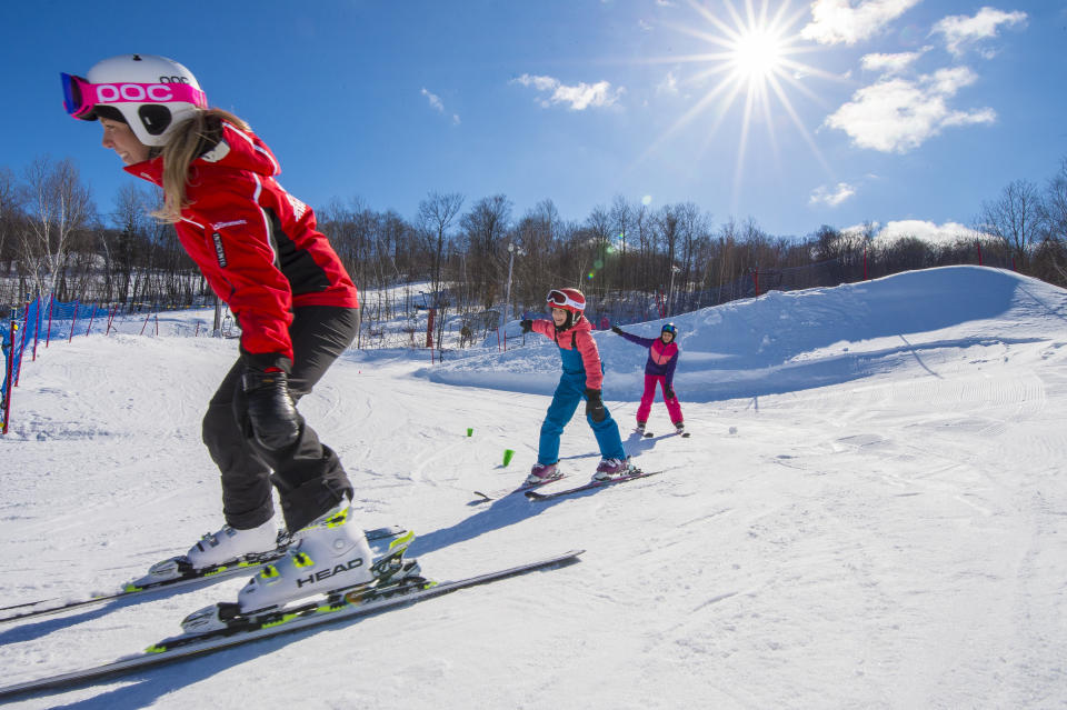 Mother and two children learning how to ski on the bunny slopes at Sommet Saint-Sauveur in Quebec, ski school