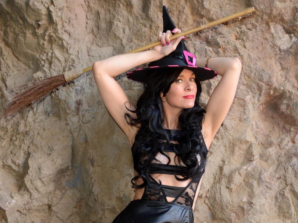 modern day witches costume with leather outfit and black hat and broom