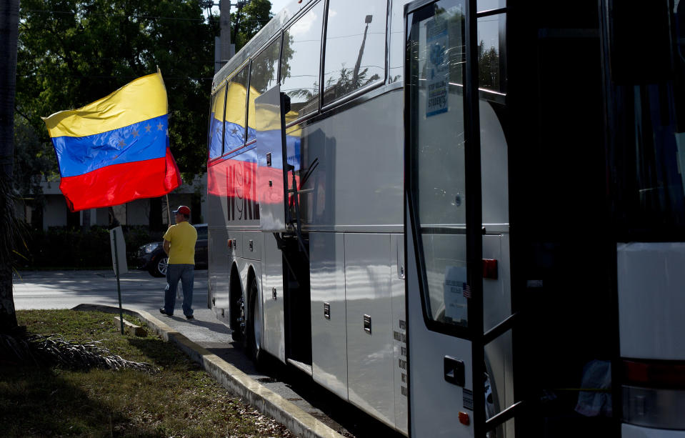 Guillermo Beltran waves his country's flag as Venezuelans from South Florida prepare for their bus trip to Washington, Thursday, May 8, 2014, in Doral, Fla. They are rallying to ask the Congress and President Barack Obama to impose economic sanctions and travel restrictions to the Venezuelan government officials because of presumed human right violations in the South American country. Organizers said they expect Venezuelans from 19 states will meet in Washington on Friday to demonstrate in front of the White House, Congress and the Organization of American States. (AP Photo/J Pat Carter)