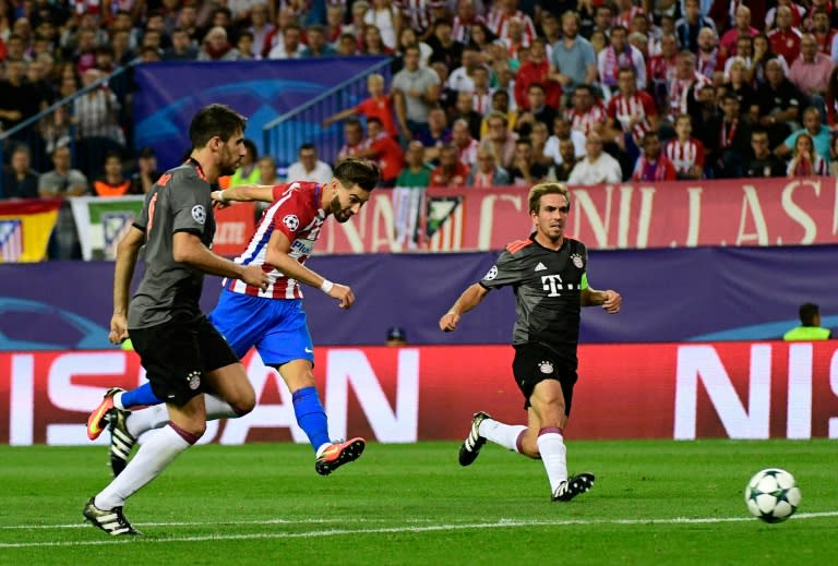 Atletico Madrid's Yannick Carrasco (C) shoots to score past Bayern Munich's Philipp Lahm (R) during their UEFA Champions League Group D match