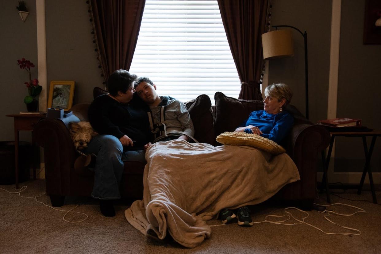 Andee Cooper, left, leaned in to talk to her son Kannon at their home on March 14, 2023, while her mother, Peggy Cooper, watched. Kannon has a rare disorder that causes him to have daily seizures and cognitive regression, which means Kannon who is 14 thinks and acts more like a toddler, his mom said. Kannon was lethargic most of the morning after having two seizures.